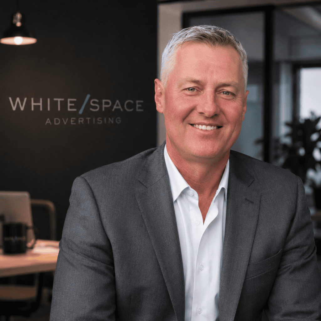 Professional businessman in office with White Space Advertising logo in background.